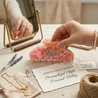 Pink acrylic hair claw with rhinestone details placed in a gift set on a table