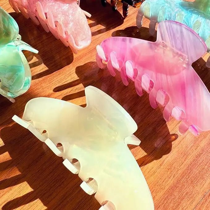 Pastel acrylic hair claws, including cream and pink, with pearl and rhinestone accents.