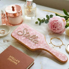 Air cushion hair brush with pink marbled cushion, wooden backing, and rhinestone script on top